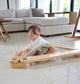 Baby playing with a Dahan Balance Beams on a tiled floor in a modern living room.